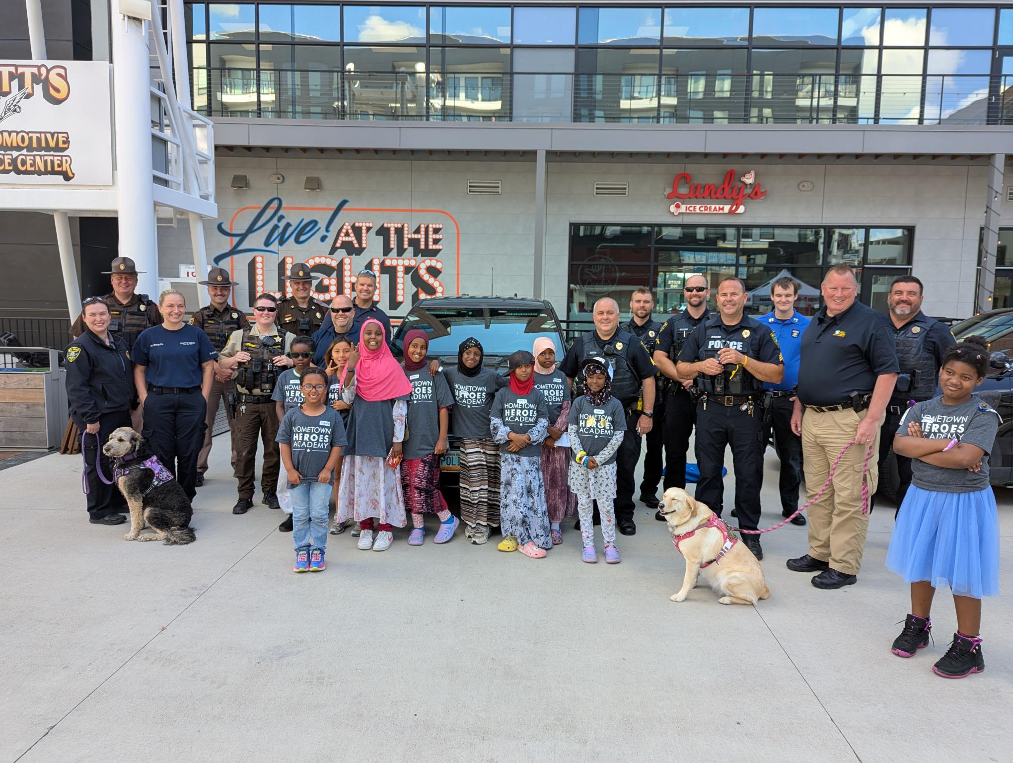 Children and community members gathered with first responders and dogs at an outdoor event